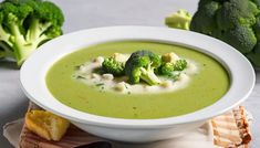 a white bowl filled with broccoli soup next to some cut up pieces of broccoli