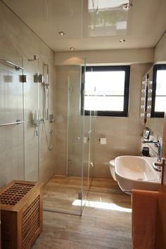 a bathroom with a walk in shower next to a sink and a toilet under a window