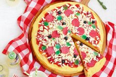 a pizza sitting on top of a red and white checkered table cloth next to a knife