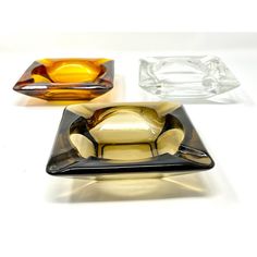 three different colored glass dishes on a white surface