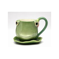 a green coffee cup with two eyes sitting on top of a leaf shaped saucer