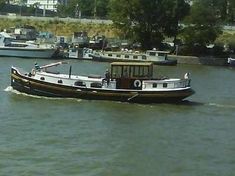 there is a boat going down the river with other boats in the water behind it