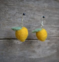 two small yellow fruits hanging from hooks on wooden planks with black bead earwires