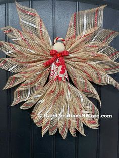 a wreath made out of burlocks and ribbon hanging on the front door with a red bow