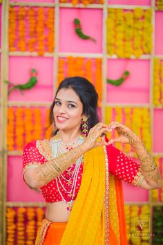 a woman in an orange and yellow lehenga with her hands on her chest