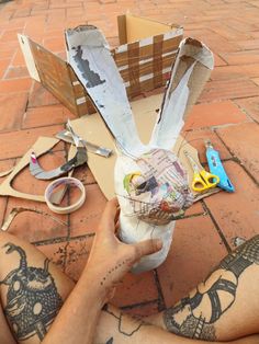 a person sitting on the ground with some scissors and paper in front of their head