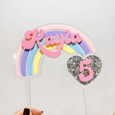 a person holding up a cake topper with the number five in front of it