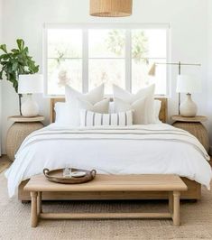 a bed with white linens and pillows in a bedroom next to a large window