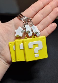 a hand holding a yellow and white keychain with two question marks on it