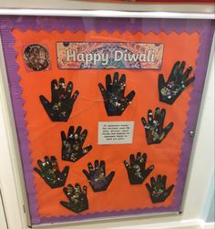 an orange and purple bulletin board with black handprints on it that says happy diwali