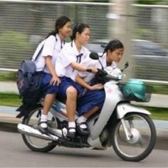 three girls riding on the back of a motorcycle