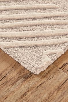 a white rug on top of a wooden floor next to a wood flooring board