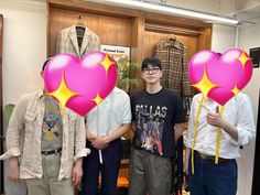 three young men standing in front of a display of shirts and ties with heart shaped balloons attached to them