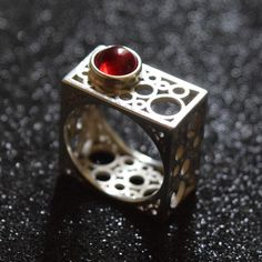 Discover the epitome of modern elegance with this handcrafted square silver ring, featuring a rich garnet centerpiece. The unique geometric design of this piece draws inspiration from contemporary architecture, offering a bold statement while maintaining a minimalist aesthetic. Each ring is meticulously crafted to highlight the natural beauty of the garnet, making it a perfect gift for those born in January or anyone who appreciates artisan jewelry. Add a touch of sophistication to any outfit with this distinctive ring. Modern Ruby Ring For Formal Occasions, Elegant Ruby Ring With Rectangular Polished Finish, Elegant Rectangular Ruby Ring With Polished Finish, Modern Ruby Wedding Ring, Modern Red Open Ring, Modern Red Ring Jewelry, Modern Silver Ruby Ring For Formal Occasions, Modern Red Ruby Ring, Modern Silver Ring With Rectangular Stone