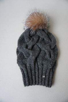 a gray knitted hat with a fur pom - pom on the top