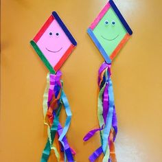 two colorful kites with faces on them are hanging from the wall next to each other