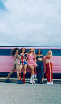 four women standing in front of a pink train