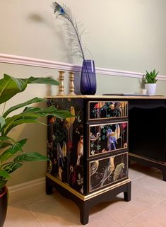 a black and gold painted dresser next to a potted plant