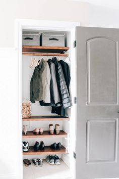 an open closet with shoes and clothes hanging on the shelves, next to a door