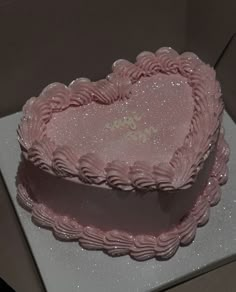 a pink heart shaped cake sitting on top of a table