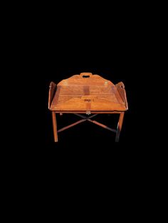 a wooden tray with two handles on it and a handle for the lid, sitting on a black background