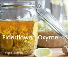 a glass jar filled with flowers and lemons next to a wooden spoon on top of a table