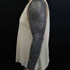 a woman with a black and grey tattoo on her arm is standing in front of a black background