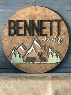 a wooden sign that says bennett charles with mountains and trees in the back ground