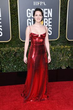 a woman in a red dress on the red carpet at an awards event with golden globes