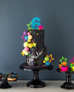 a birthday cake with stars and confetti on the top is surrounded by cupcakes