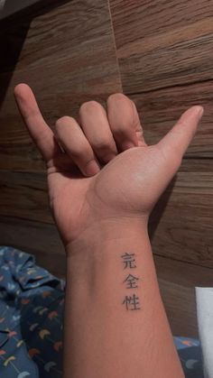 a person with a tattoo on their arm making the peace sign