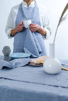 a woman standing in front of a table holding a cup