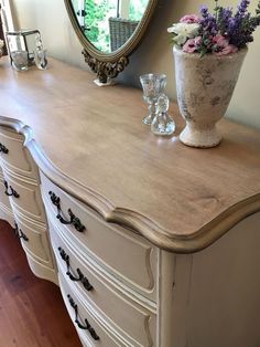 a white dresser with flowers on it and a mirror