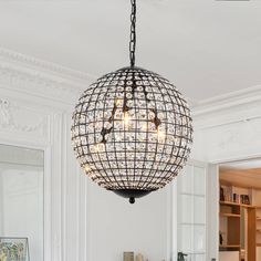 a chandelier hanging from the ceiling in a room with white walls and furniture