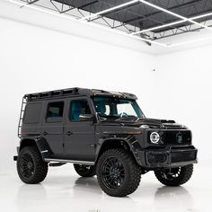 a black mercedes g - class is parked in a white room with an overhead ceiling