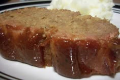 a piece of meat sitting on top of a white plate next to mashed potatoes