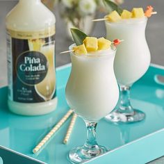 two glasses filled with drinks sitting on top of a blue tray