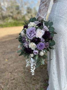 a bride holding a bouquet of purple and white flowers