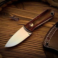 a knife sitting on top of a wooden table next to a leather sheath and wallet