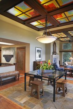 a dining room with a glass table surrounded by wooden benches and colorful stained glass windows