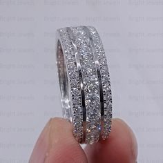 someone is holding two wedding rings in their hand, with diamonds on the inside and outside