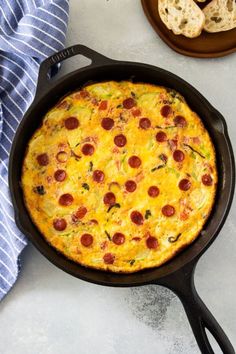 a pepperoni and cheese pizza in a cast iron skillet next to some bread