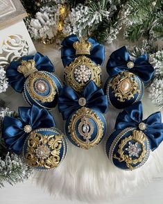 blue and gold christmas ornaments with bows on white furnishing next to pine tree