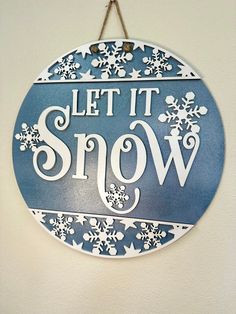 a sign that says let it snow hanging from a wall with snowflakes on it