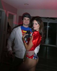 a man standing next to a woman in a red and white outfit with superman on her chest