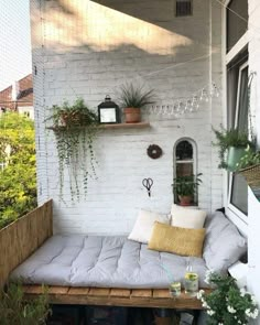 a white brick wall with some plants on it and a couch in the foreground