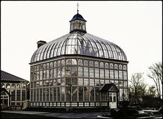 a large glass building with a clock on the top of it's roof and windows