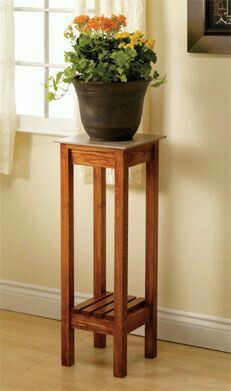 a potted plant sitting on top of a wooden stand in front of a window