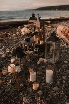 candles and flowers are on the ground next to some rocks near the water with an ocean in the background