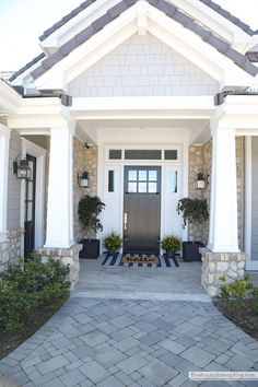 the front entrance to a house with two potted plants on either side and an entry door